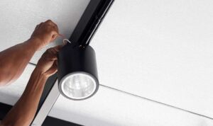 A person inspecting a home electrical outlet for discoloration and signs of overheating.