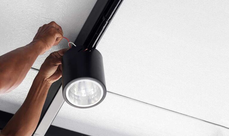 A person inspecting a home electrical outlet for discoloration and signs of overheating.