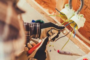 A homeowner watches a ceiling light flicker while an electrician checks the nearby electrical panel. KEYWORDS: ["flickering ceiling light", "residential electrical panel", "electrician inspecting wiring"]